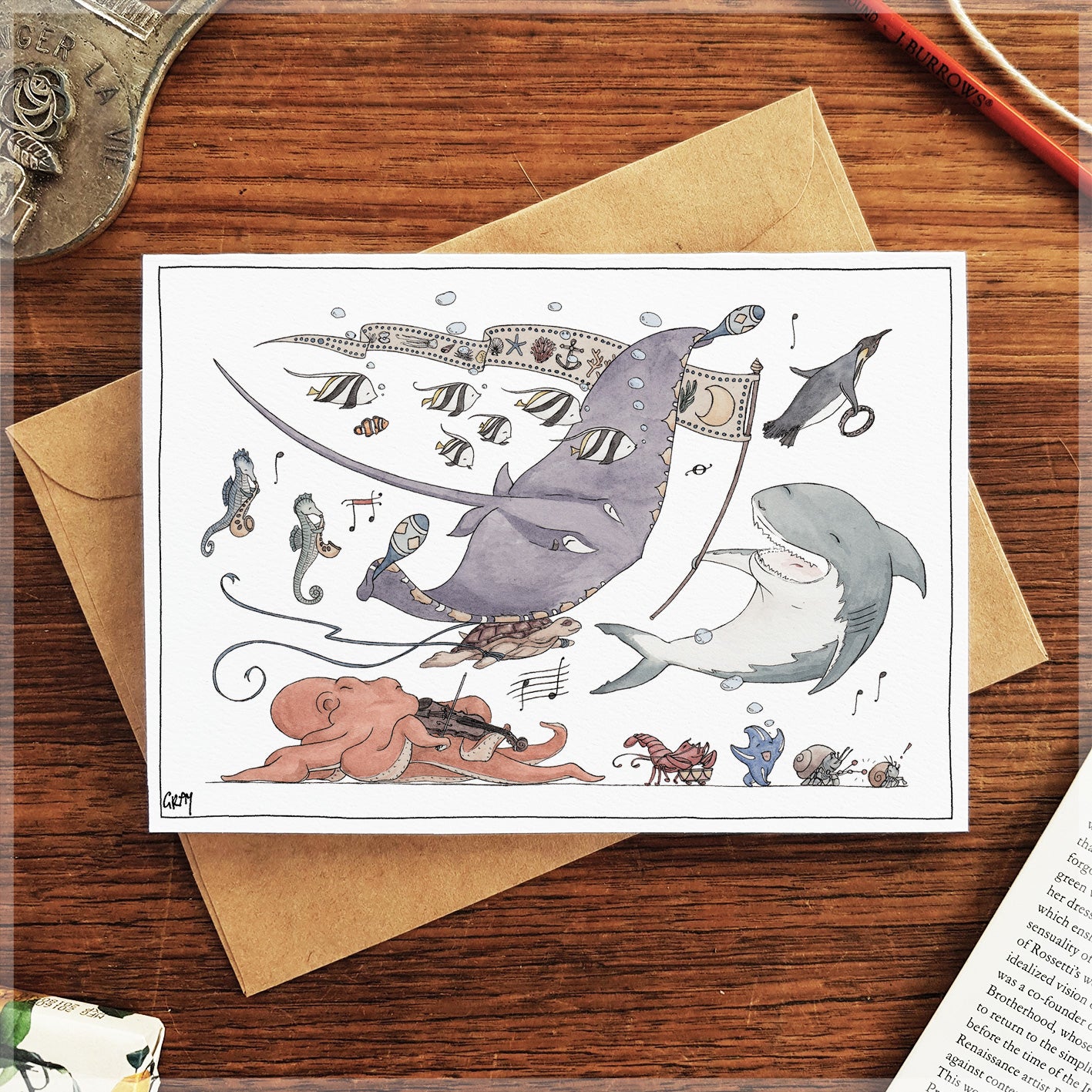 Illustrated card with sharks and musical elements on a wooden surface with an envelope.